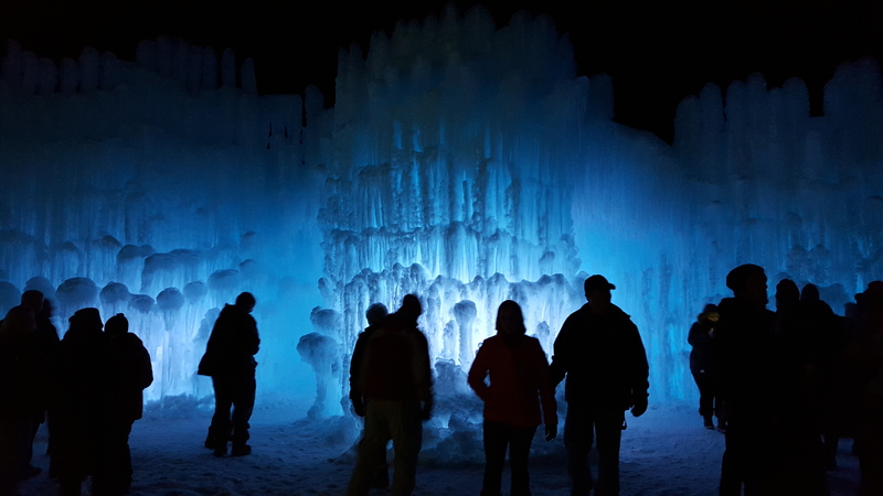 People walking around the ice castle with blue lighting