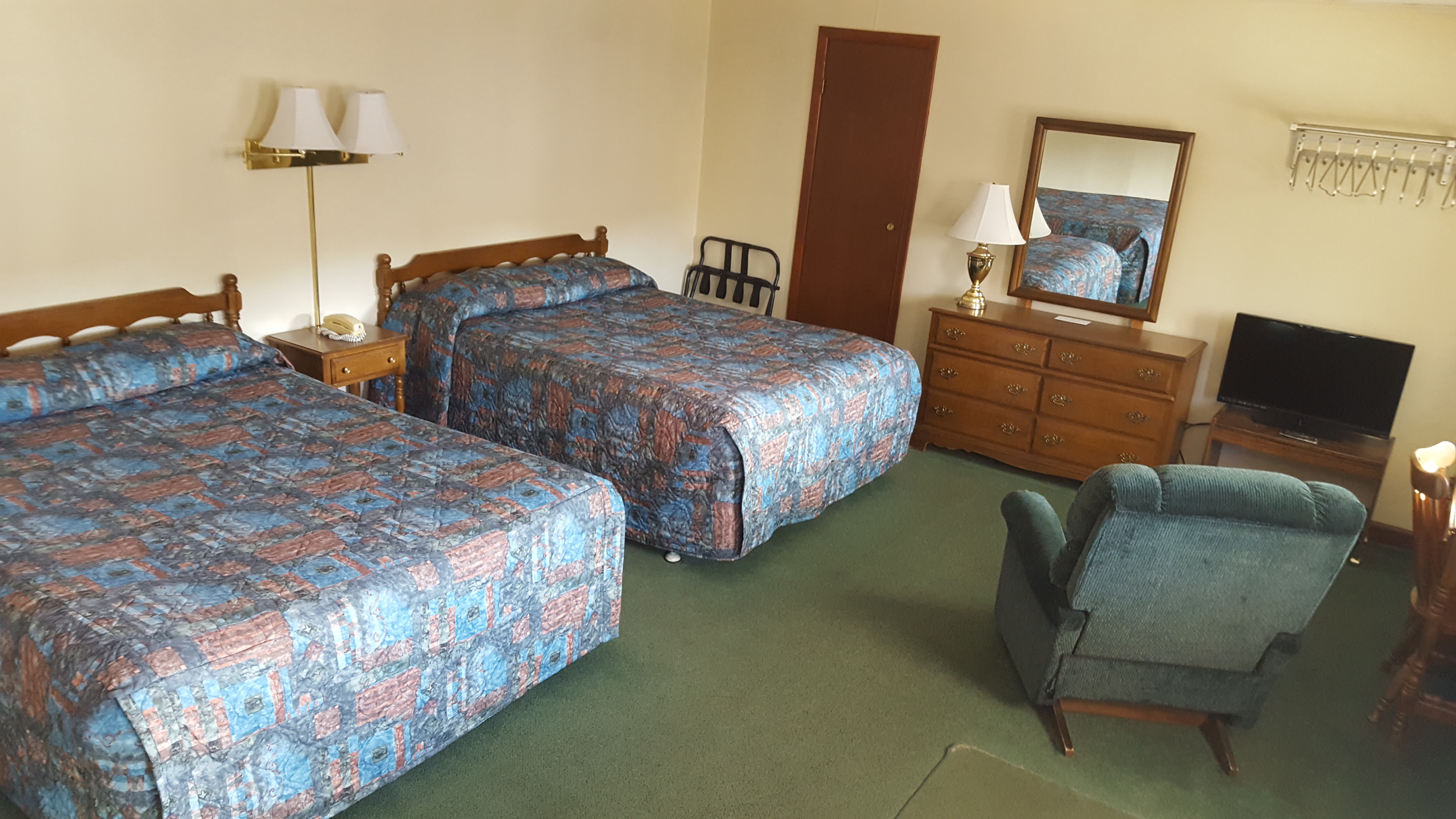 Motel room with two beds and recliner.
